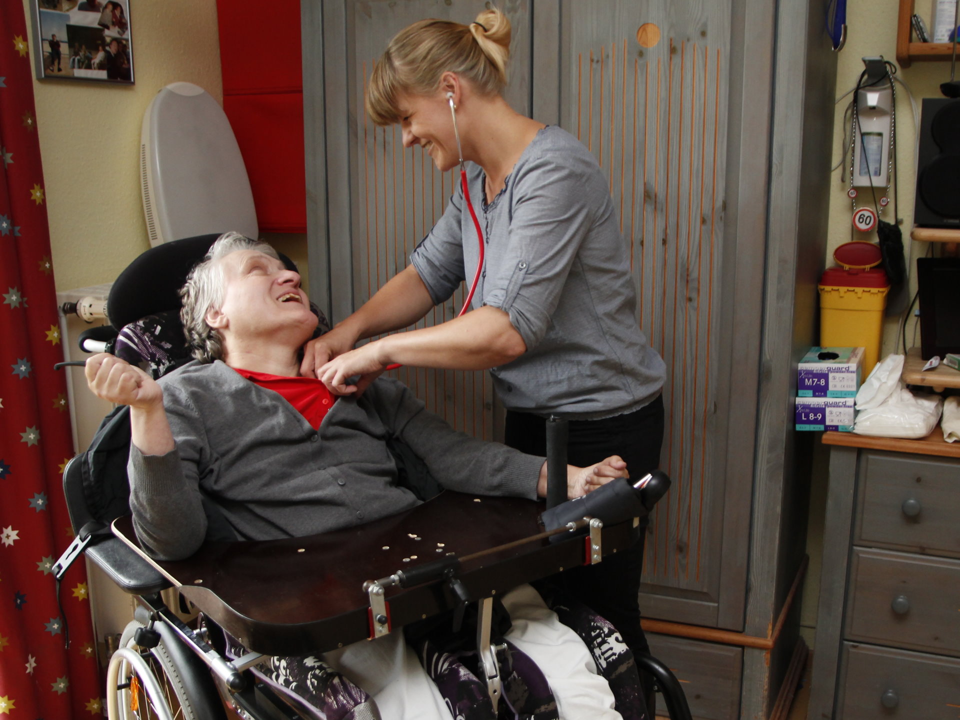 Eine Frau im Rollstuhl wird mit einem Stethoskop abgehört 