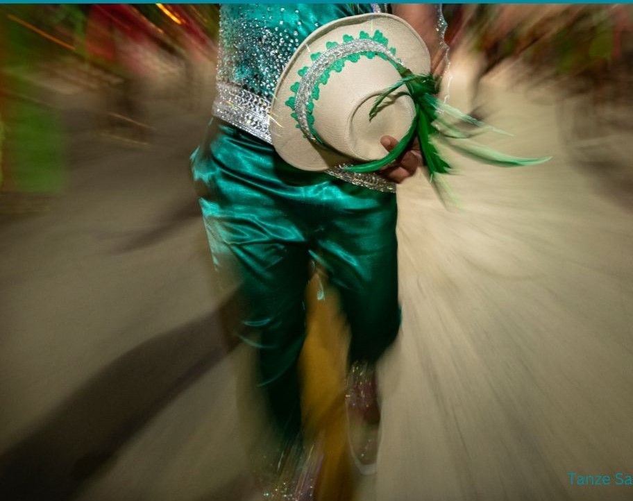 Die Beinen eines Mannes in einer grünen glänzenden Hose tanzen.