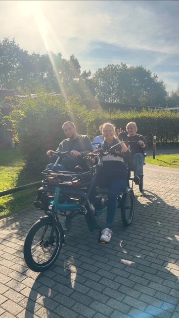 Vier Menschen fahren im Gegenlicht der Sonne auf einem Spezialrad zusammen und freuen sich.