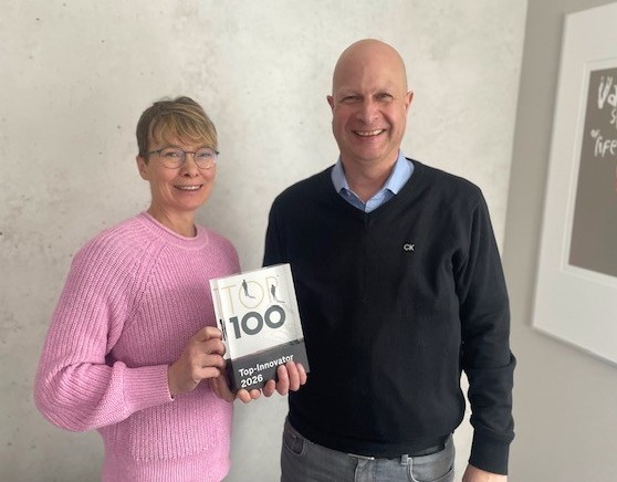 Geschäftsführende Lars Wellbrock und Mara Hopp halten einen Preis mit der Aufschrift Top 100 Innovator in den Händen. 